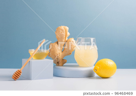 Antioxidant drink fresh ginger lemon honey glass trendy blue background, podium minimalism, balance 96468469