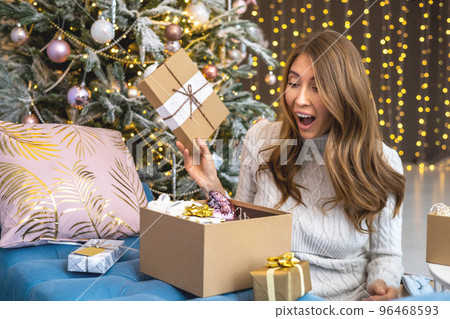 Amazement woman open craft gift box desired present celebrating winter holiday at Christmas tree Amazement woman open craft gift box desired present celebrating winter holiday at Christmas tree 96468593