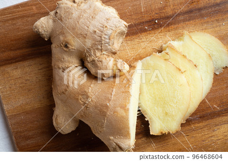 cutting fresh ginger spice at wooden desk. Healthy concept cutting fresh ginger spice at wooden desk. Healthy concept 96468604
