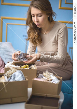 Woman opening festive Christmas package gifts and sweets candy for winter holiday Woman opening festive Christmas package gifts and sweets candy for winter holiday 96468650