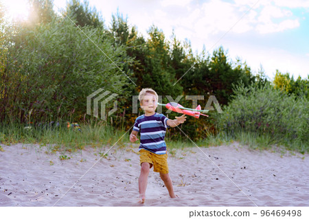 caucasian little boy launching toy plane into the air caucasian little boy launching toy plane into the air 96469498