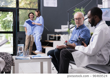 Physician measuring old patient blood pressure and hypertension with tonometer instrument during consultation in hospital reception. Medic checking cardiac pulse and doing cardiology examination Physician measuring old patient blood pressure and hypertension with tonometer instrument during consultation in hospital reception. Medic checking cardiac pulse and doing cardiology examination 96469524