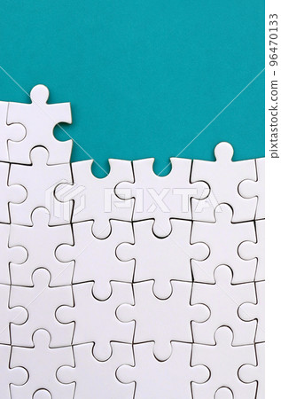 Fragment of a folded white jigsaw puzzle on the background of a blue plastic surface. Texture photo with copy space for text 96470133