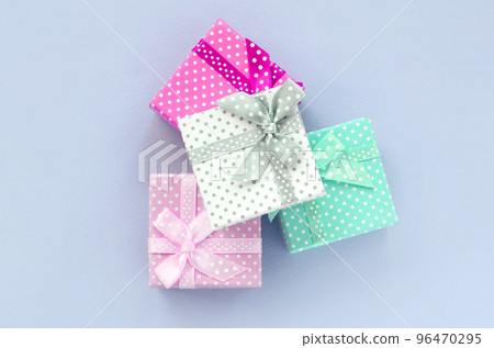 Pile of a small colored gift boxes with ribbons lies on a violet background Pile of a small colored gift boxes with ribbons lies on a violet background 96470295