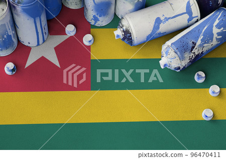 Togo flag and few used aerosol spray cans for graffiti painting. Street art culture concept 96470411