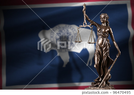 Wyoming US state flag with statue of lady justice and judicial scales in dark room. Concept of judgement and punishment 96470495