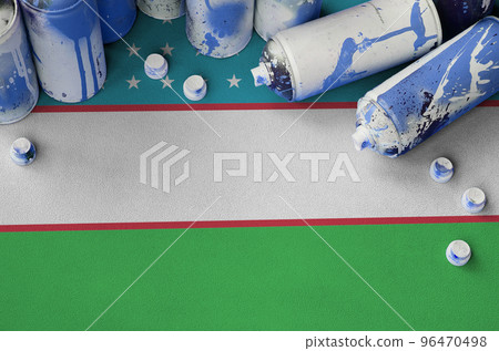 Uzbekistan flag and few used aerosol spray cans for graffiti painting. Street art culture concept Uzbekistan flag and few used aerosol spray cans for graffiti painting. Street art culture concept 96470498