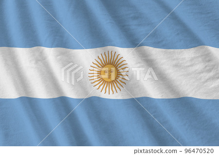 Argentina flag with big folds waving close up under the studio light indoors. The official symbols and colors in banner 96470520