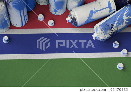 Gambia flag and few used aerosol spray cans for graffiti painting. Street art culture concept 96470583