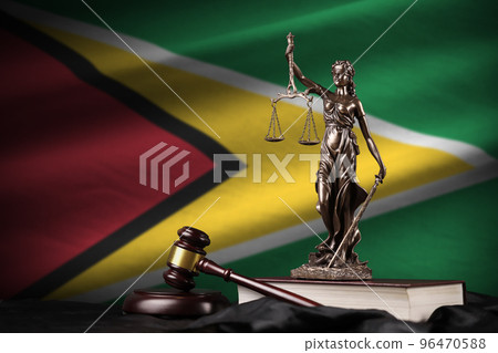 Guyana flag with statue of lady justice, constitution and judge hammer on black drapery. Concept of judgement and guilt Guyana flag with statue of lady justice, constitution and judge hammer on black drapery. Concept of judgement and guilt 96470588