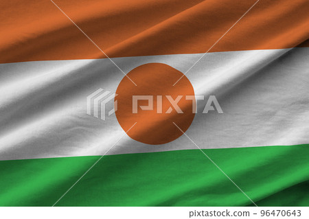 Niger flag with big folds waving close up under the studio light indoors. The official symbols and colors in banner 96470643