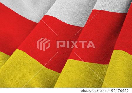 South Ossetia flag with big folds waving close up under the studio light indoors. The official symbols and colors in banner 96470652