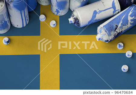 Sweden flag and few used aerosol spray cans for graffiti painting. Street art culture concept Sweden flag and few used aerosol spray cans for graffiti painting. Street art culture concept 96470684