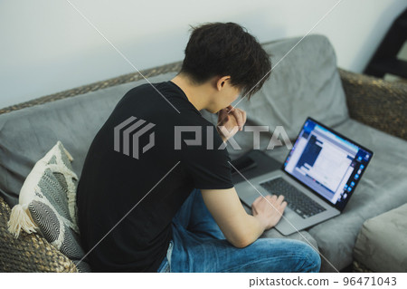 A man looking at a computer in the living room　 96471043