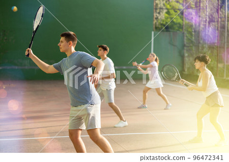 Male sportsman preparing to hit ball with racket. Frontenis game on outdoor court 96472341