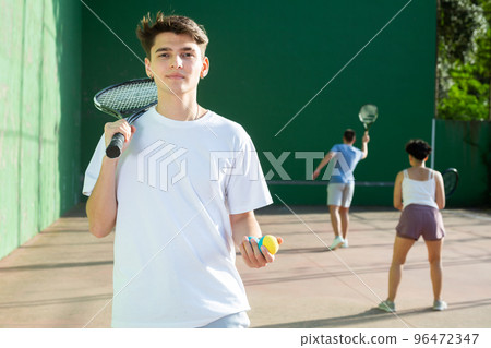 Portrait of caucasian boy standing on frontenis court, holding racket and ball 96472347