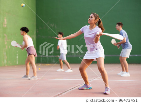 Young Latina playing pelota on open court on summer day 96472451