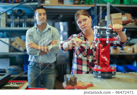 Woman assembling plumbing fixture under control of skillful man 96472471
