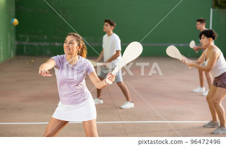 Woman Basque pelota player hitting ball with wooden racket 96472496