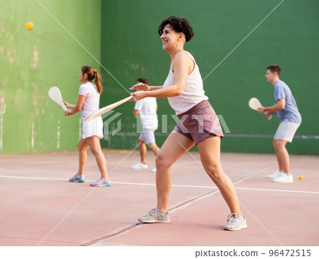 Sporty woman performing basic strokes during paleta fronton group training 96472515