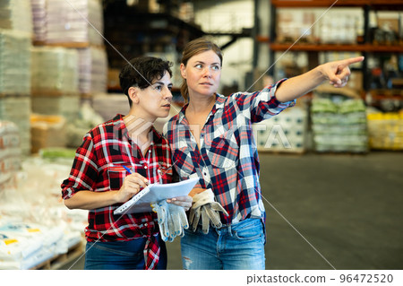 Women dicsussing stock control in warehouse Women dicsussing stock control in warehouse 96472520