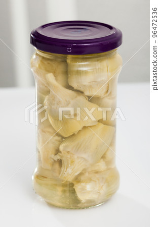 Glass jar with tasty preserved artichokes on table, nobody Glass jar with tasty preserved artichokes on table, nobody 96472536