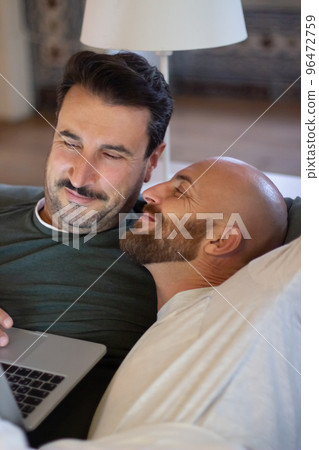 Happy gay lying in bed and looking with tenderness at his lover Happy gay lying in bed and looking with tenderness at his lover 96472759