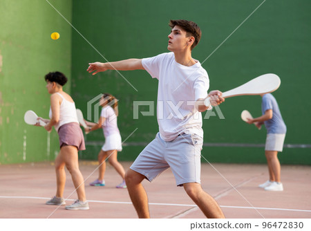Young male pelota player hitting ball with wooden racket 96472830