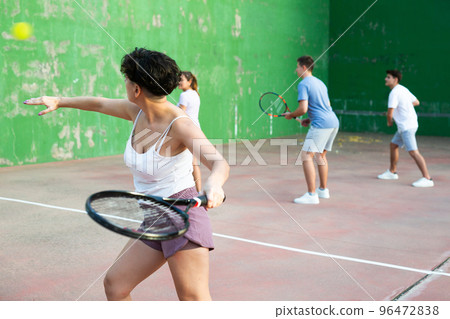 Sportive woman in shorts and t-shirt playing frontenis on court 96472838