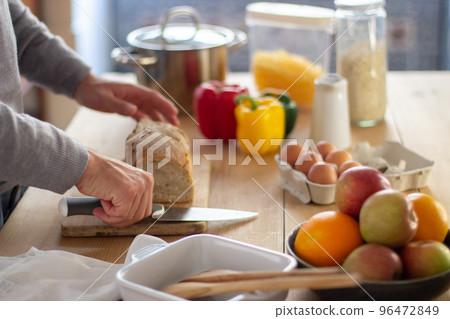 Close-up of male hands cutting loaf of bread with knife Close-up of male hands cutting loaf of bread with knife 96472849
