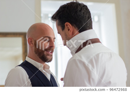 Cheerful man tying partners necktie in hotel room 96472988