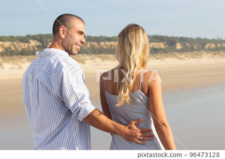 Back view of affectionate couple walking on beach 96473128