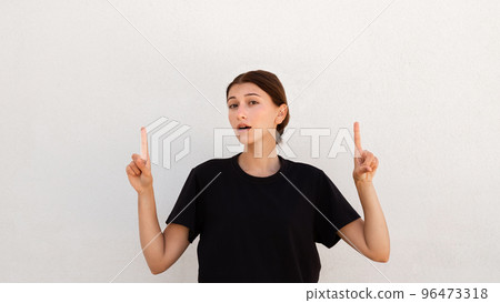 Portrait of confident young woman pointing upwards Portrait of confident young woman pointing upwards 96473318