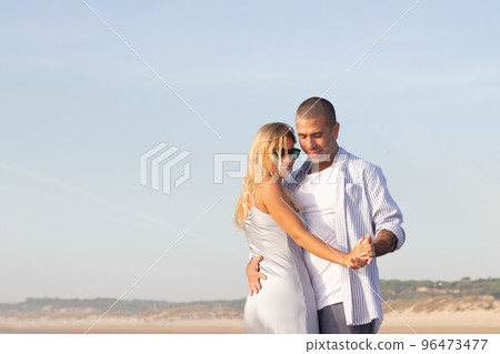 Contented male and female couple spending time at beach Contented male and female couple spending time at beach 96473477