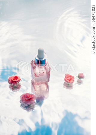 Transparent bottle on the surface of blue water with ripples and flowers Transparent bottle on the surface of blue water with ripples and flowers 96473822