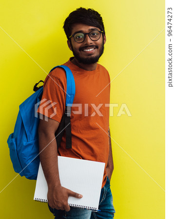 Indian student with blue backpack, glasses and notebook posing on green background. The concept of education and schooling. Time to go back to school 96474273