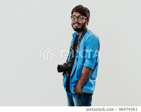 Professional photographer having DSLR camera taking picture.Indian man photography enthusiast taking photo while standing on blue background. Studio shot 96474361