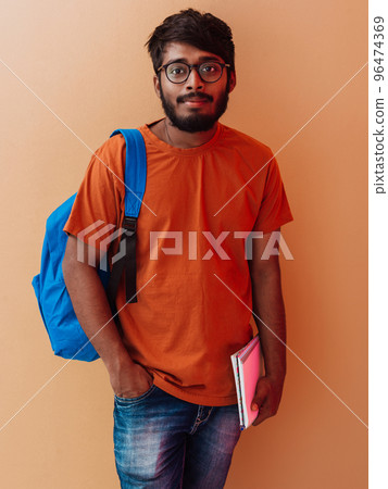 Indian student with blue backpack, glasses and notebook posing on orange background. The concept of education and schooling. Time to go back to school 96474369