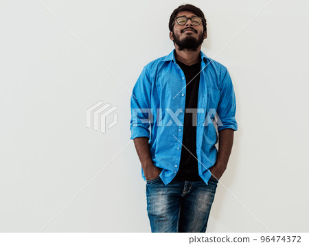 Indian smiling young man with blue shirt and glasses posing on gray background 96474372