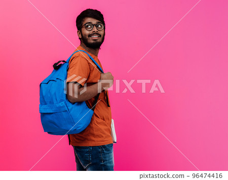 Indian student with blue backpack, glasses and notebook posing on pink background. The concept of education and schooling. Time to go back to school 96474416