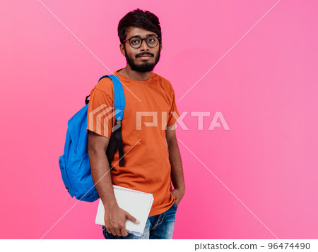 Indian student with blue backpack, glasses and notebook posing on pink background. The concept of education and schooling. Time to go back to school 96474490