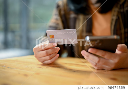 An Asian hipster girl using her smartphone and credit card to pay online bills. close-up image An Asian hipster girl using her smartphone and credit card to pay online bills. close-up image 96474869
