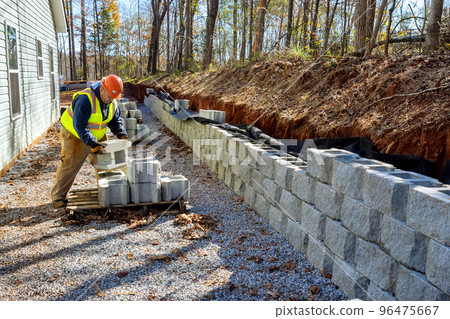 Contractor was seen installing concrete block wall that is being built on part new retaining wall construction project 96475667