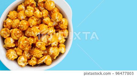 Honey caramel popcorn on blue background. 96477803