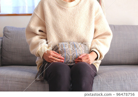 一個女人用熱水瓶熱身 一個女人用熱水瓶熱身 96478756