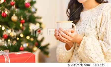 Christmas concept, Young asian woman sitting on chair near christmas tree and holding coffee cup Christmas concept, Young asian woman sitting on chair near christmas tree and holding coffee cup 96479898