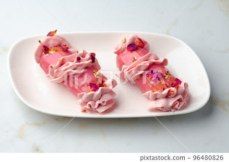 Eclair dessert with pink icing on white table Eclair dessert with pink icing on white table 96480826