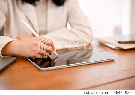 A businesswoman working on her task, using digital tablet touchpad to design her work process A businesswoman working on her task, using digital tablet touchpad to design her work process 96481983