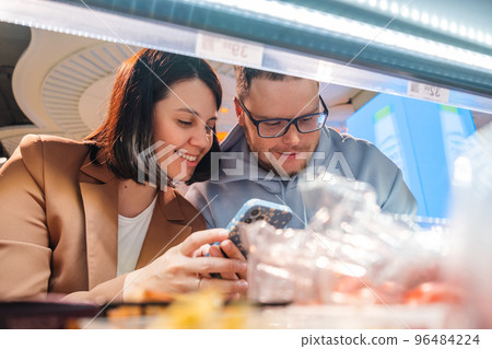 Woman and man looking for Products on Shelf Couple Customers Shopping With Checklist 96484224