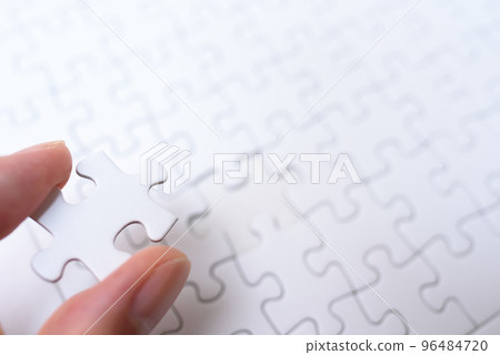 Jigsaw puzzle background texture Hand holding one remaining piece Last piece 96484720